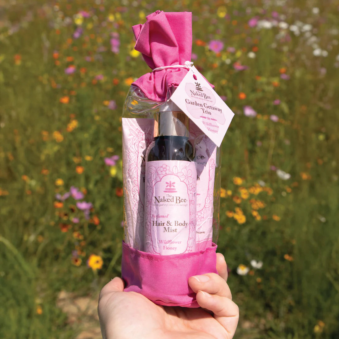 hand holding a wildflower giftset in front of a meadow filled with flowers