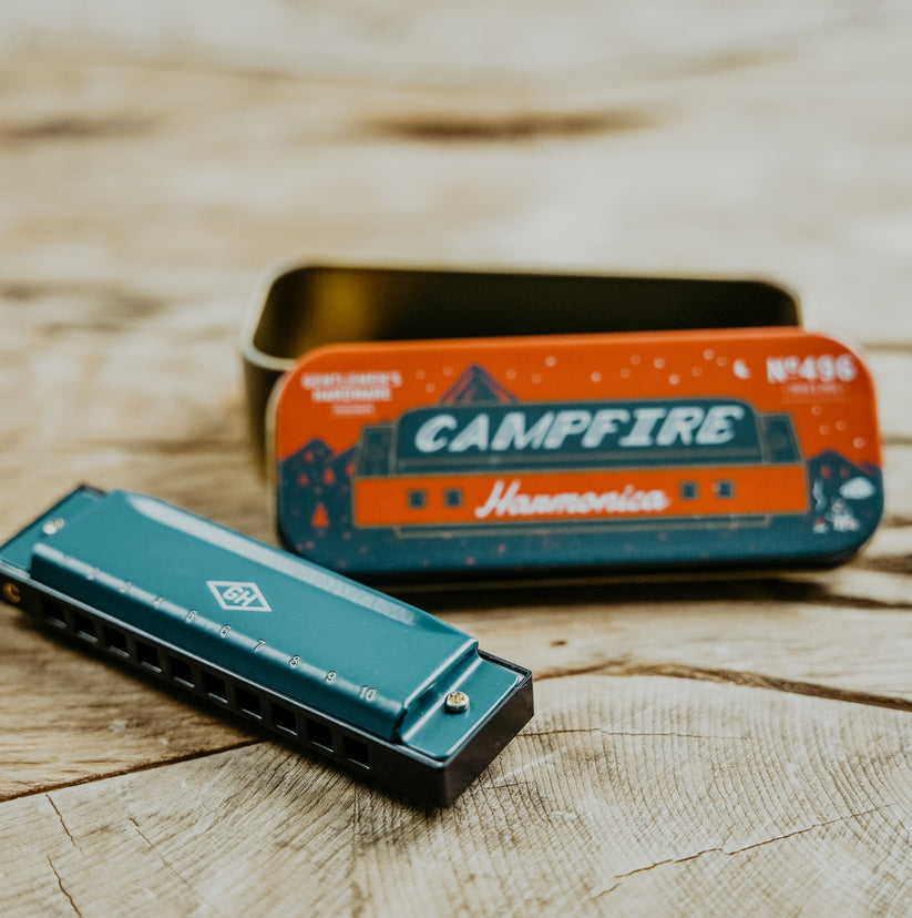 harmonica and tin case on a wooden background.