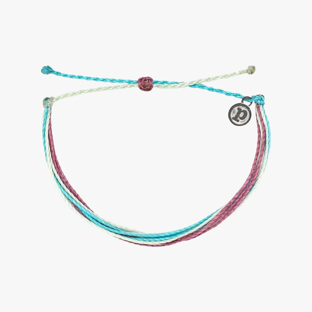 Pura Vida multi strand corded bracelet in varying shades of teal, purple, and pale green with a Pura Vida logo charm