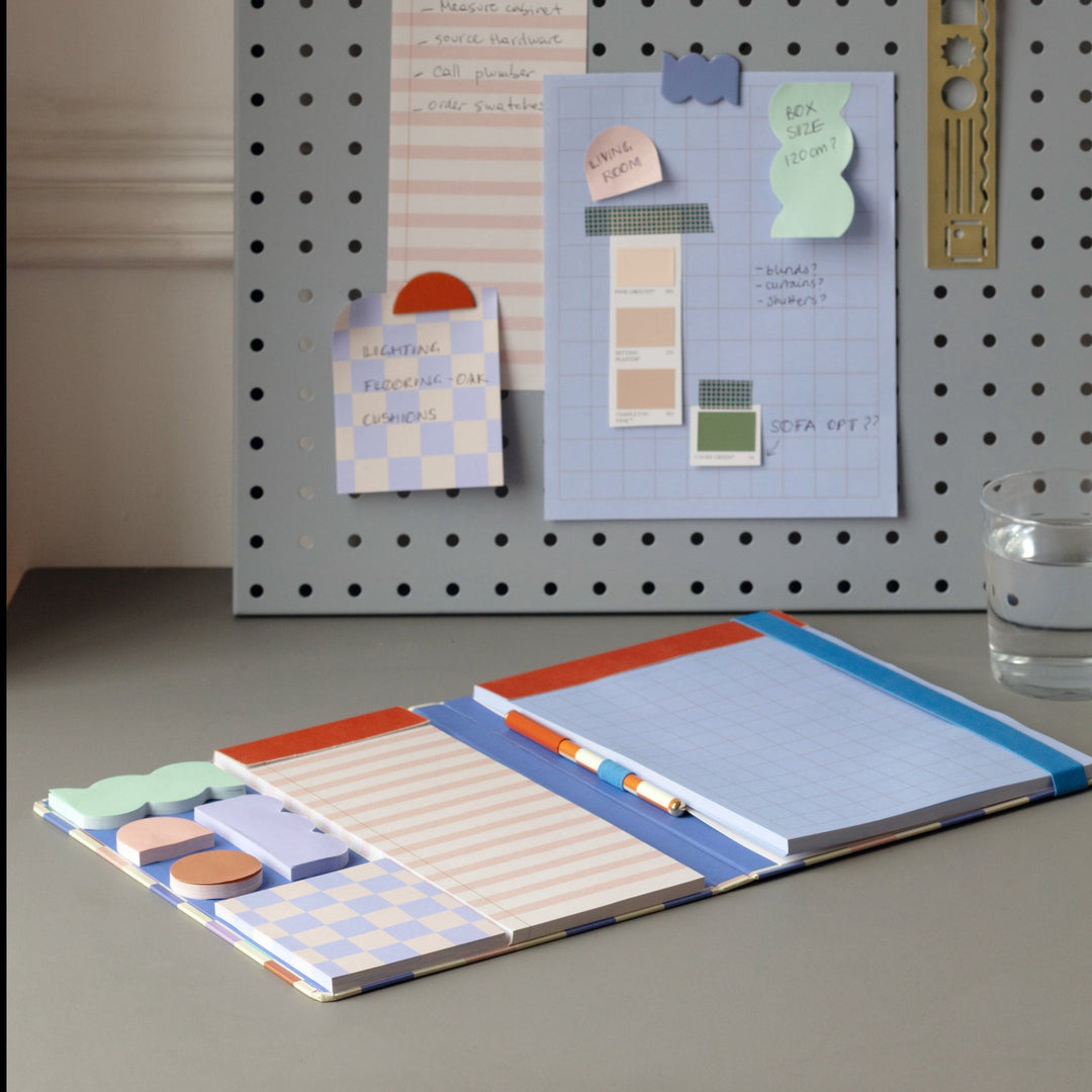 note book open showing pen, sticky note, and other note pad inside