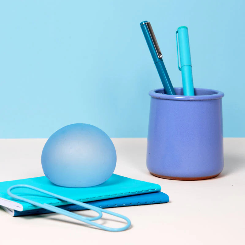 blue stress ball set on a desk with notebooks and pens.