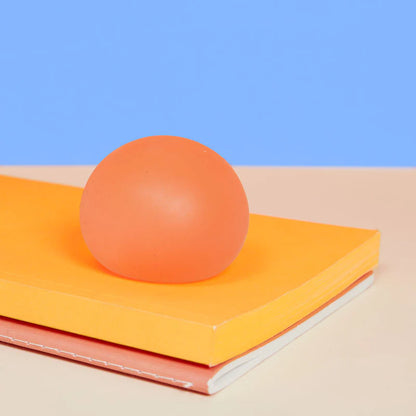 Orange stress ball on a yellow book with a blue background