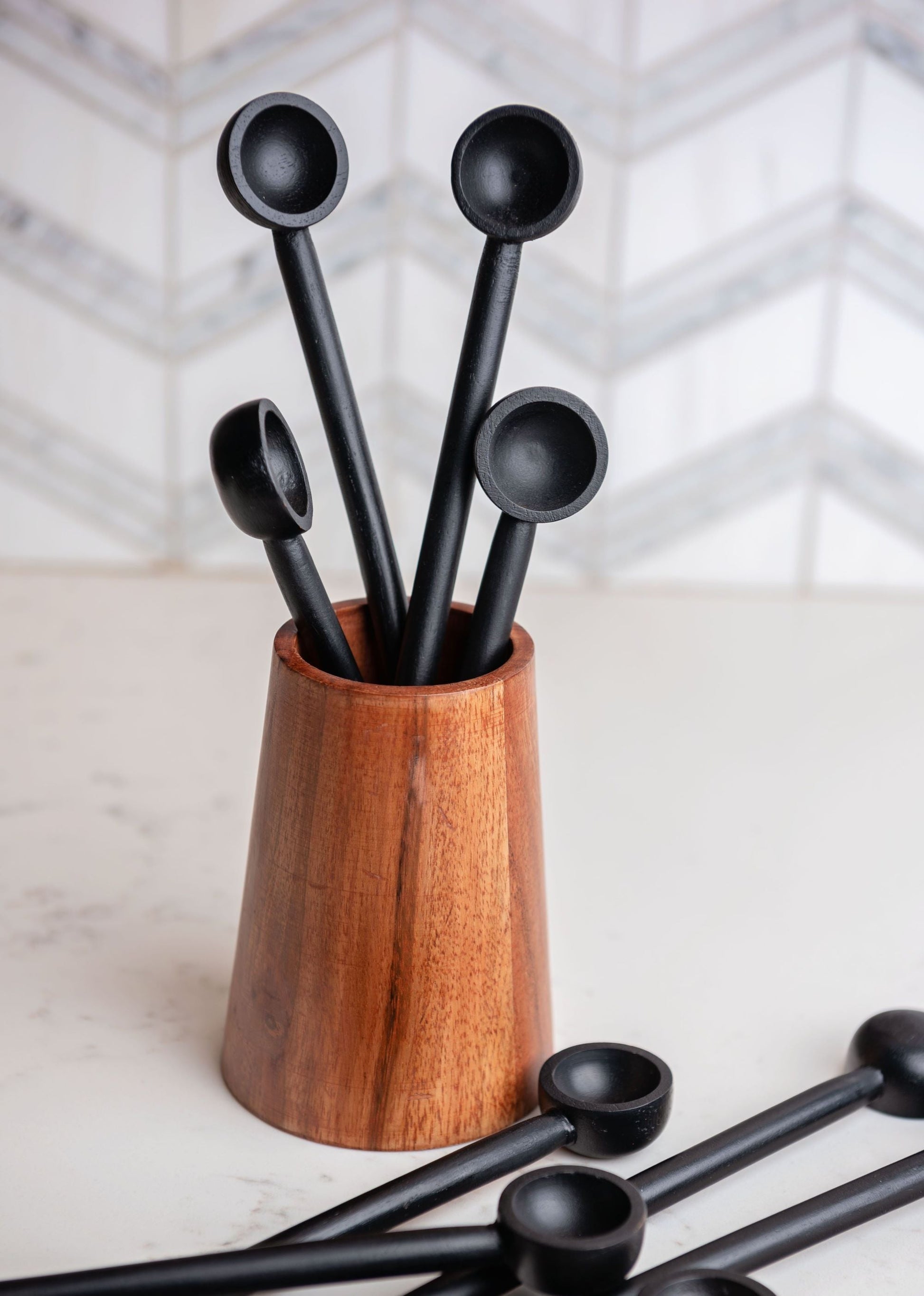 small wooden vase filled with black spoons.