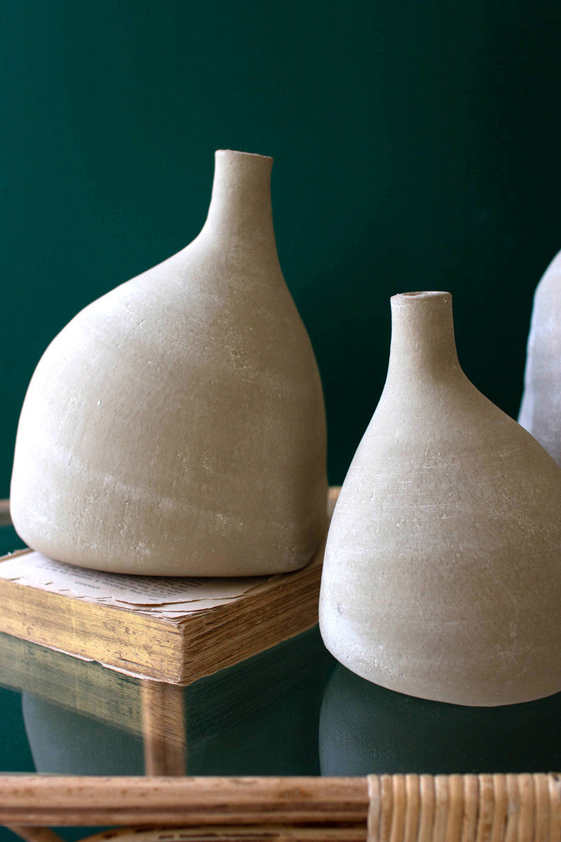 close-up of medium vase set on a book and and small vase set next to it.