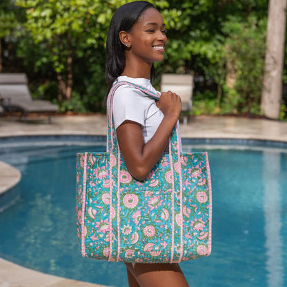 person holding a floral tote bag by a poolside