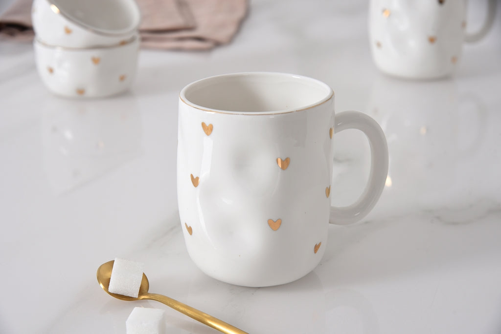 white mug with gold hearts on it on a marble surface