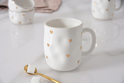 white mug with gold hearts on it on a marble surface