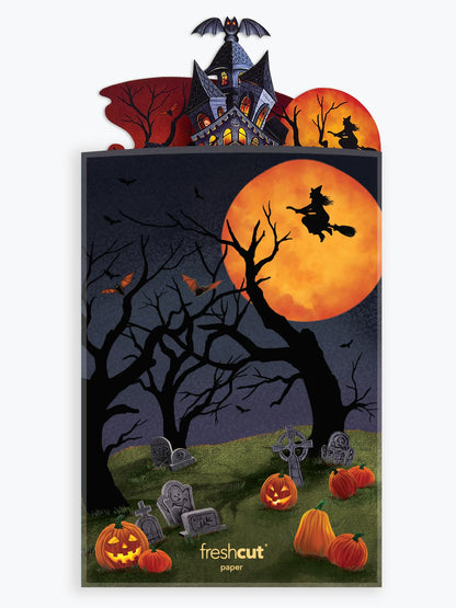 envelope for haunted house pop up card printed with image of graveyard scene and with on broom flying in front of the moon