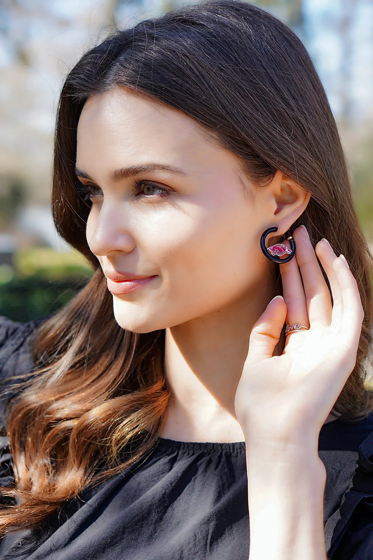 person wearing black hoops with razorback pendant in them.