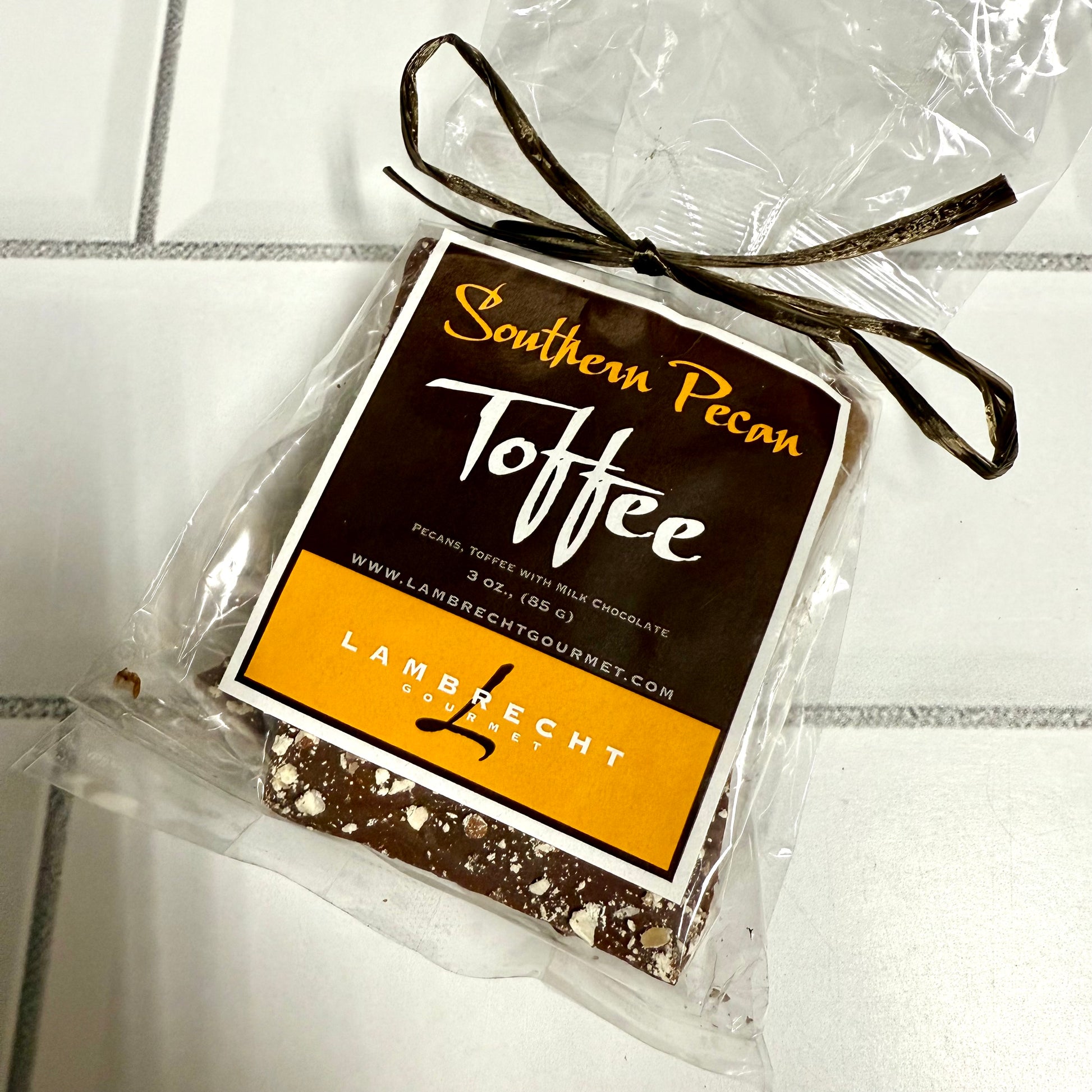 Packaged Southern Pecan Toffee with a clear wrapper on a tiled surface