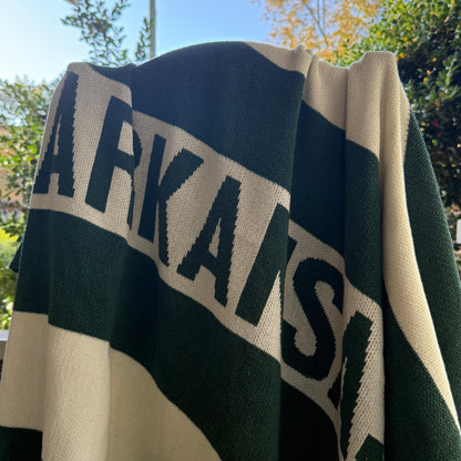 green and off-white knit Blanket with 'ARKANSAS'  text on it draped over a chair outdoors