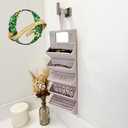 pink jewelry case hung on wall and filled with glasses and jewlery