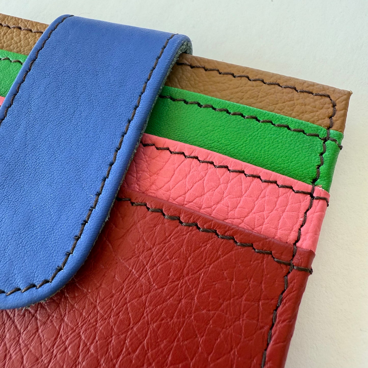 Close-up of a colorful leather wallet with pink , green, and red card slots.