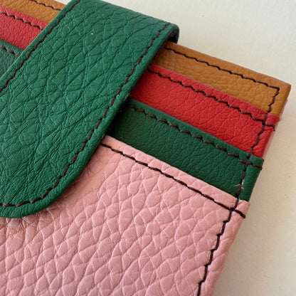 Close-up of a colorful leather wallet with green, red, and pink card slots.