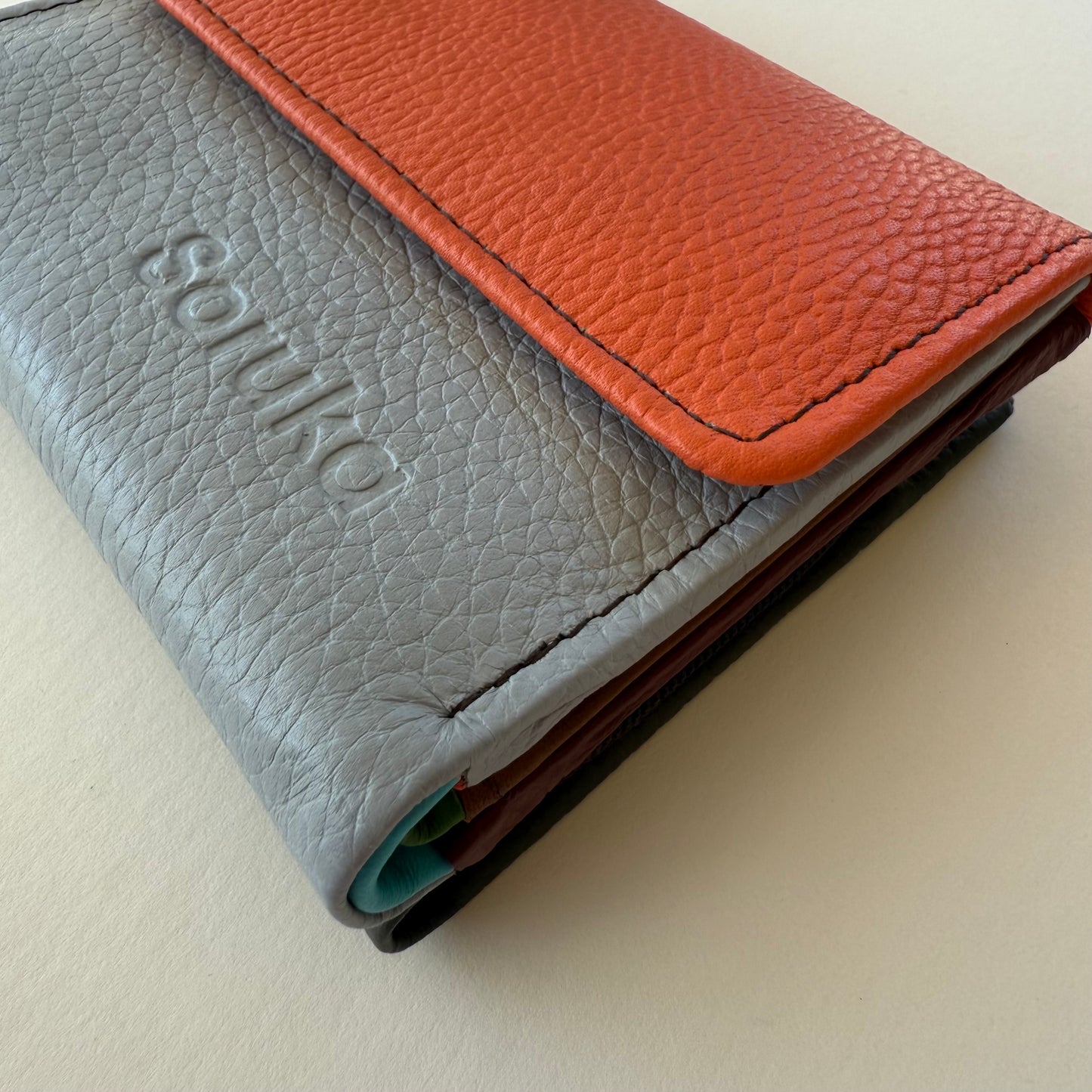 side view of Two-tone leather wallet  on a light beige background