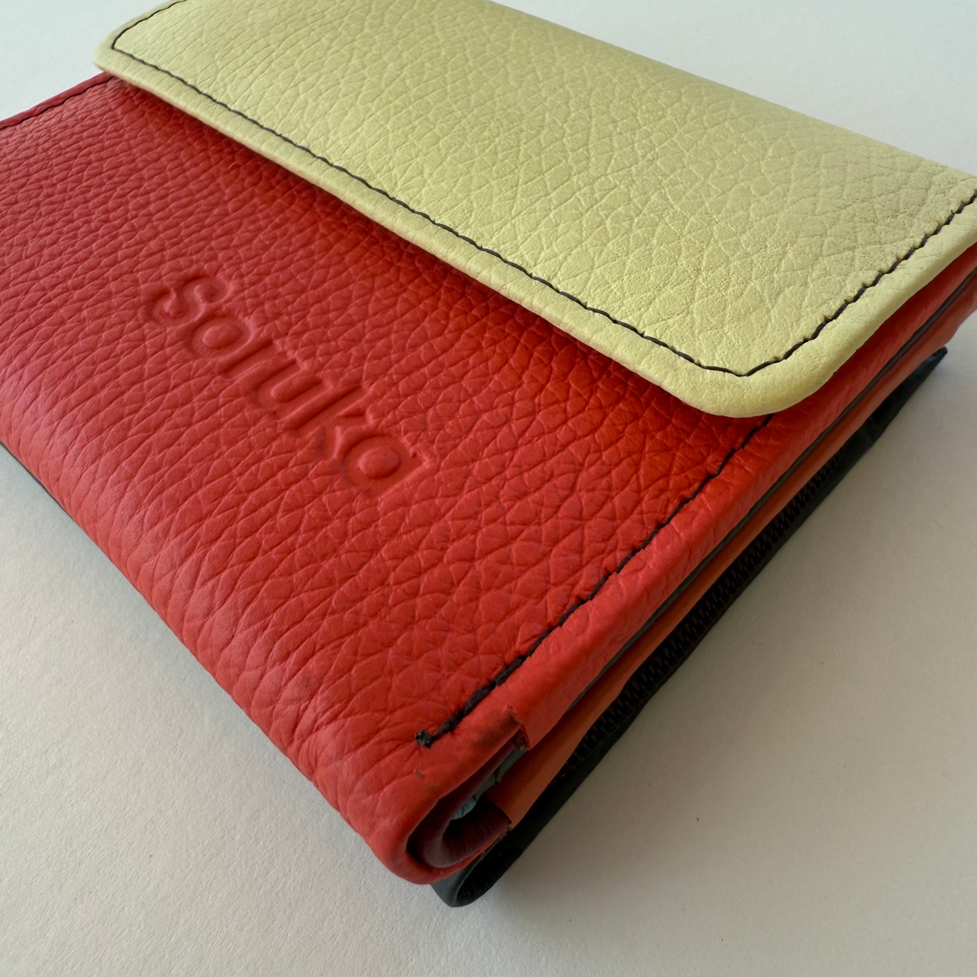 side view of Red leather wallet with yellow flap on a white background