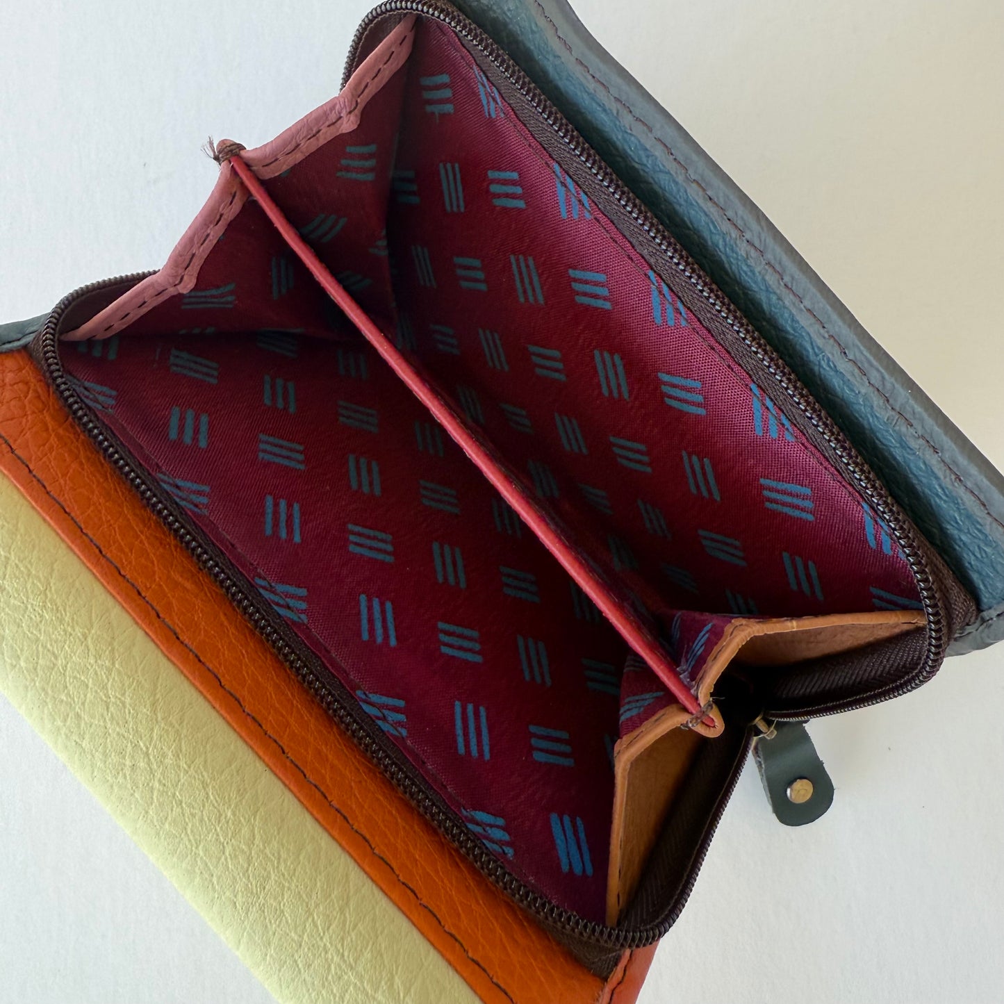 Open coin pouch on  leather wallet with patterned interior on a white background