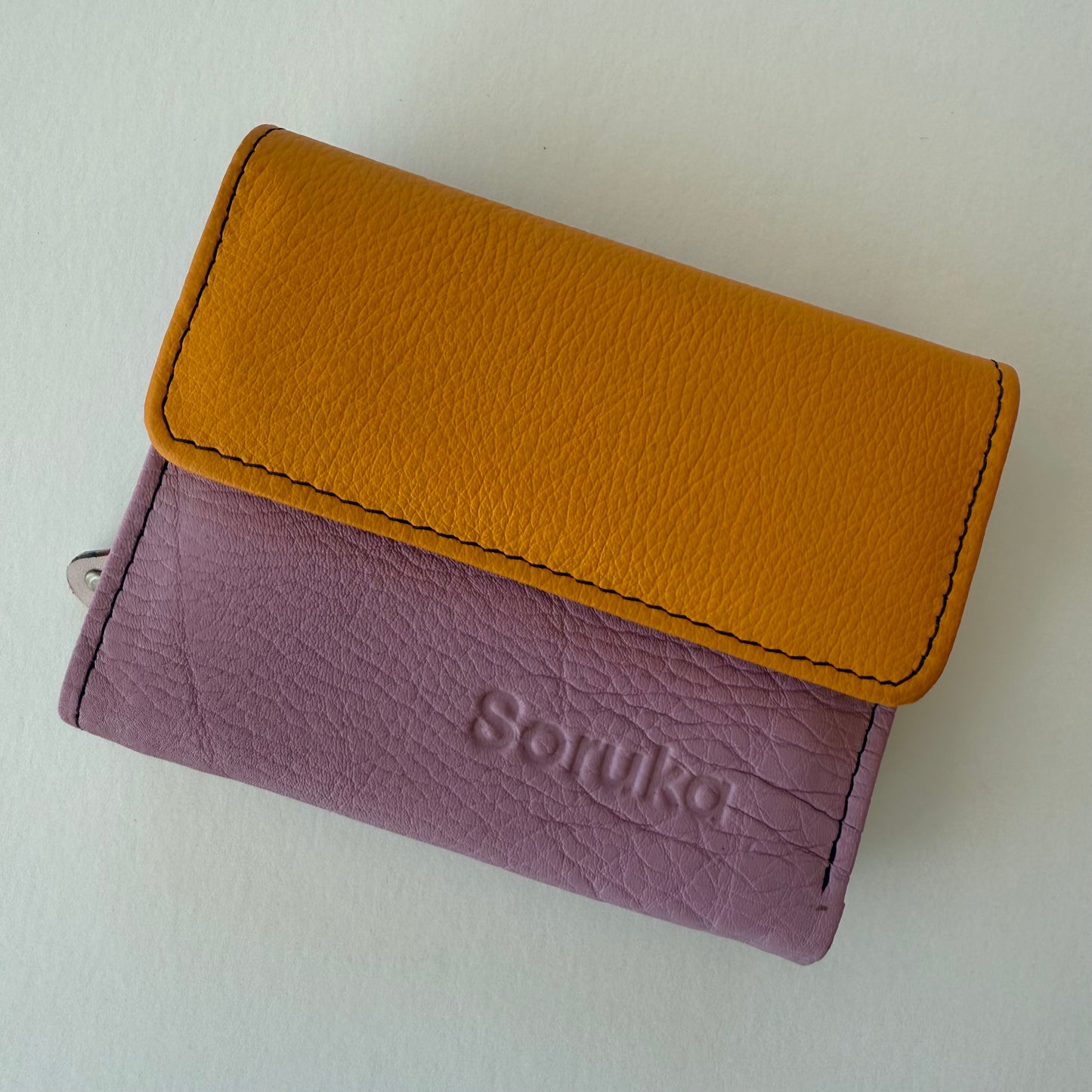 Two-tone wallet with mustard top section and purple bottom section on a white background
