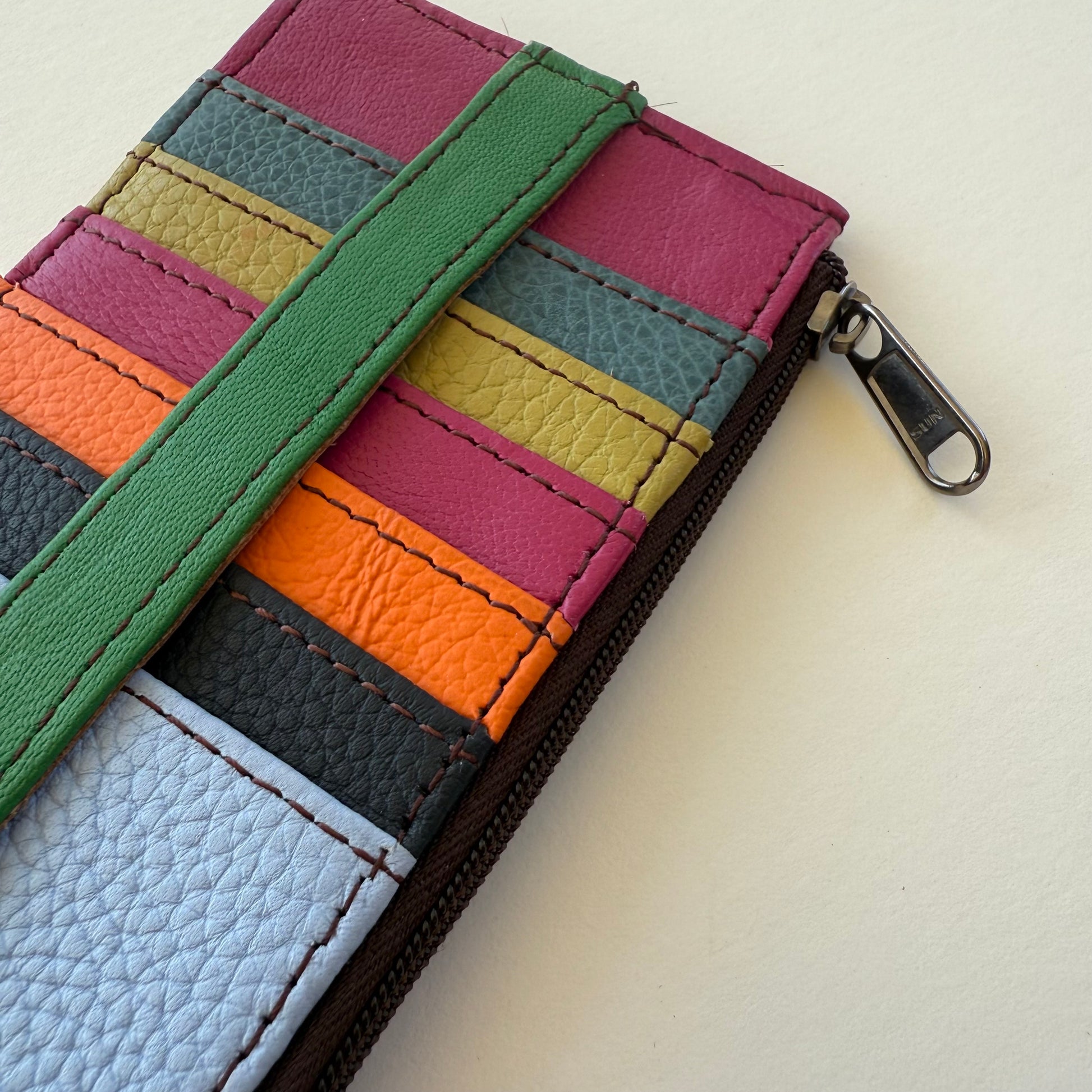 close-up of Colorful striped wallet with a green strap on a light background