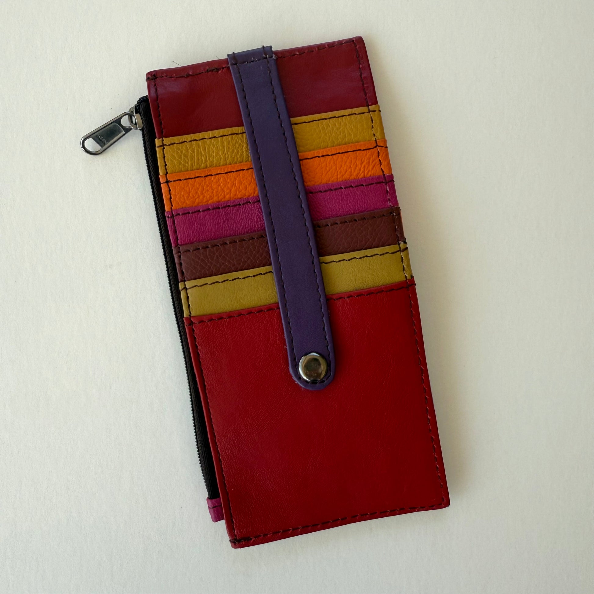 Multicolored wallet with colorful card slots and a purple strap on a light gray background