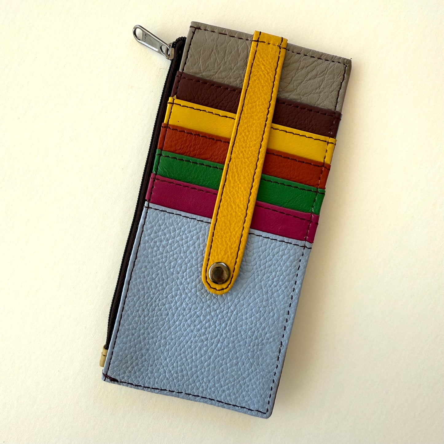 Multicolored wallet with colorful card slots and a yellow strap on a light background