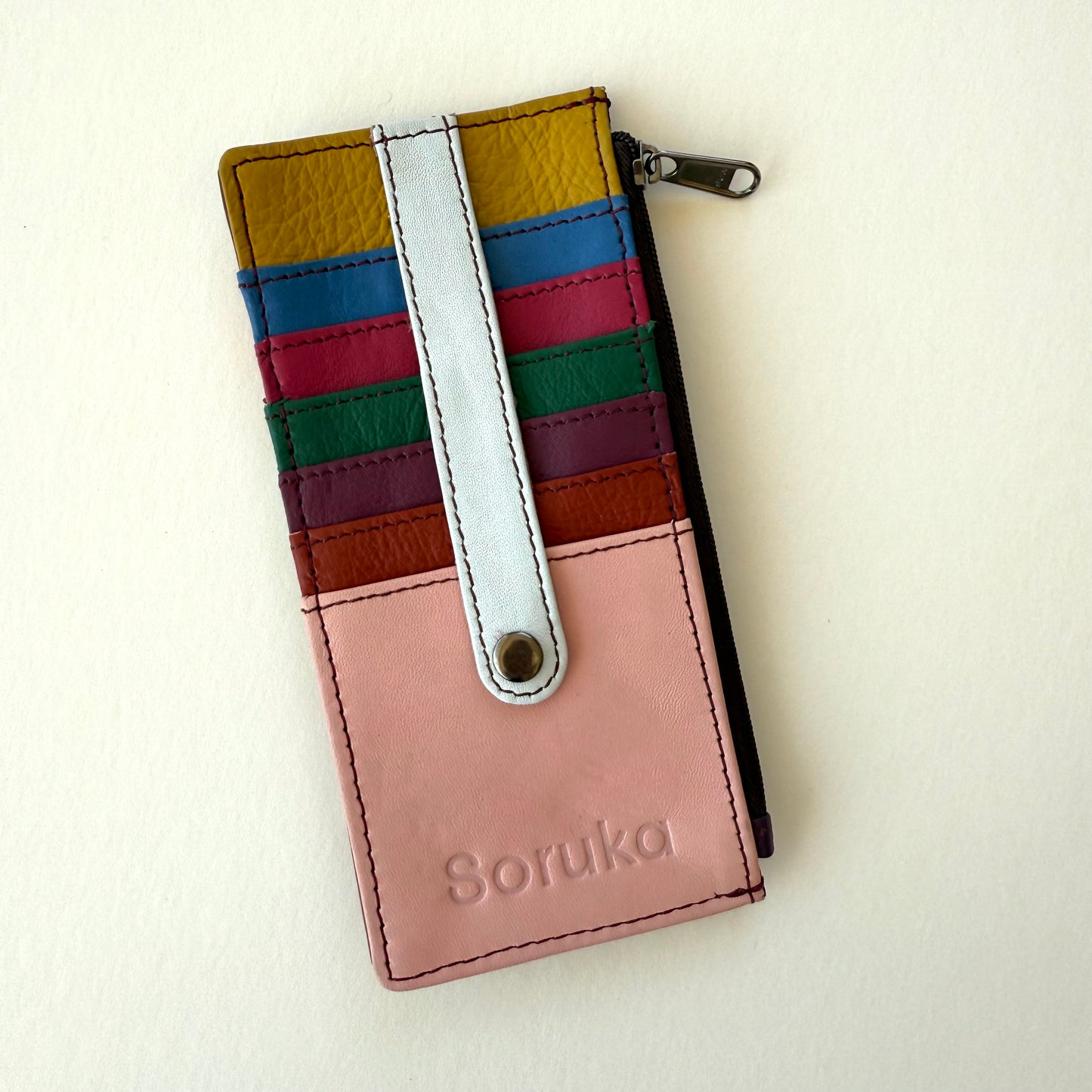 multicolored wallet with colorful card slots and strap over them shown on a white background