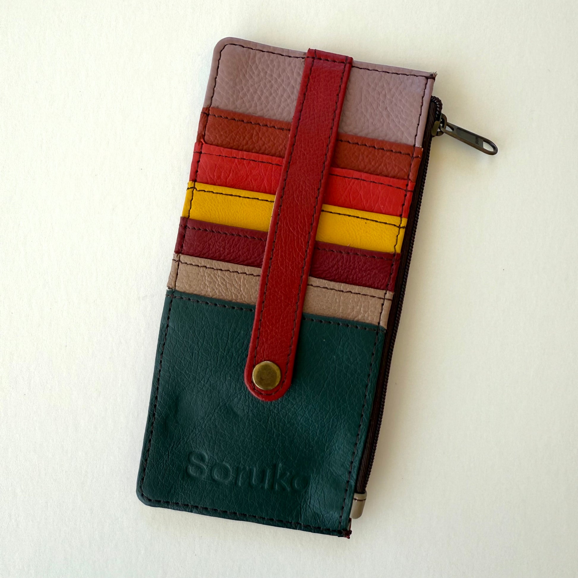 Multicolored wallet with colorful card slots and  a strap over them on a white background