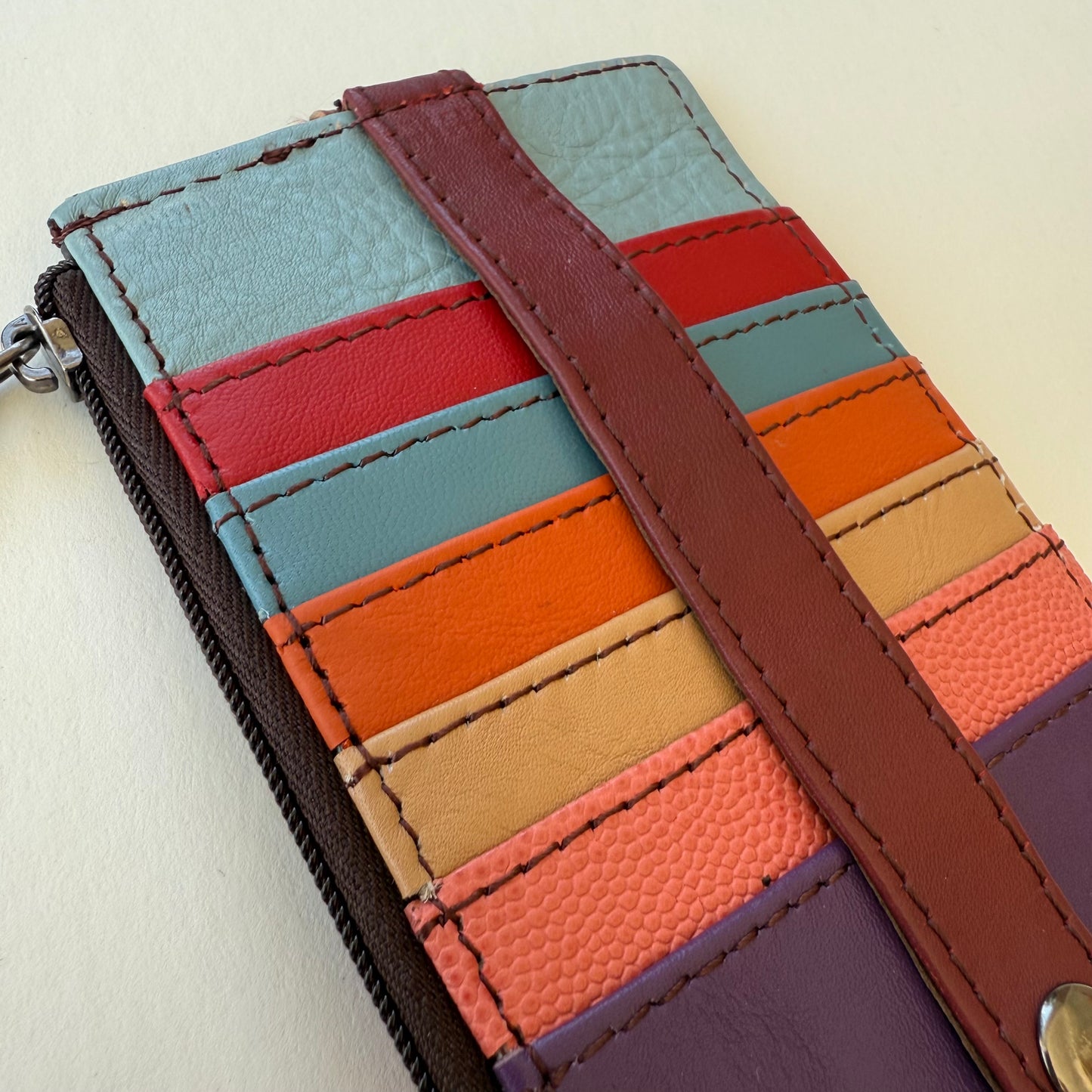 Close-up of colorful leather wallet with a strap on a light background