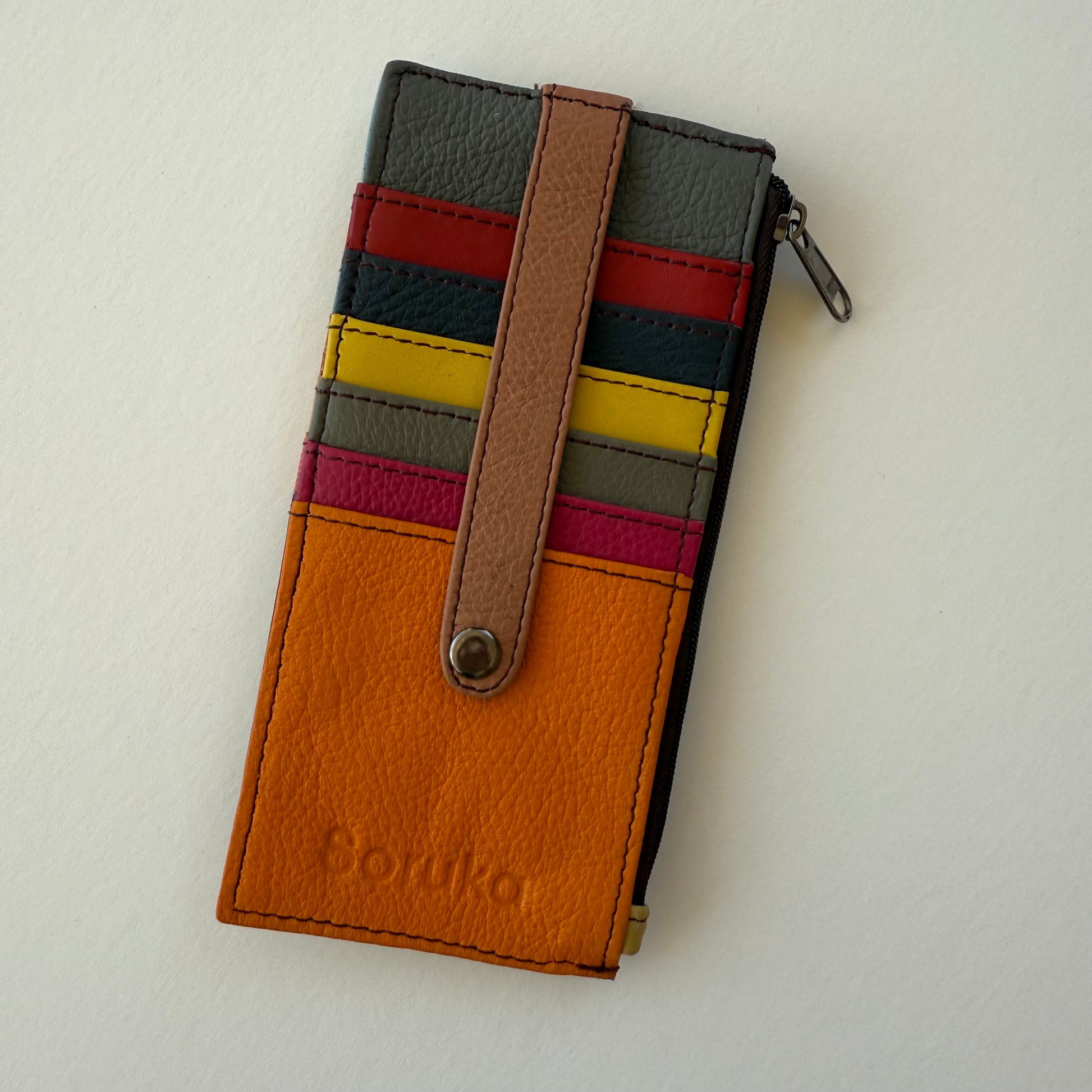 Multicolored leather wallet with a strap over card slots on a light gray background