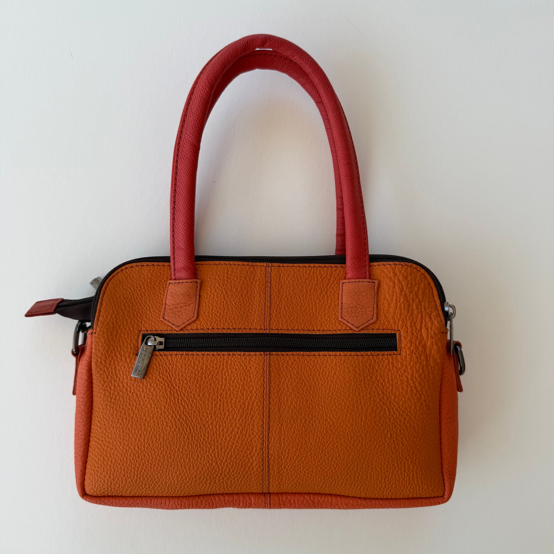 back view of orange handbag with zippered pocket