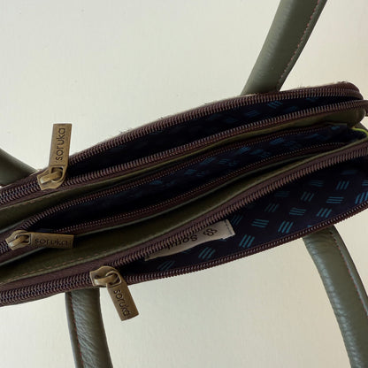 top view of green leather handbag with 3 zippered compartments