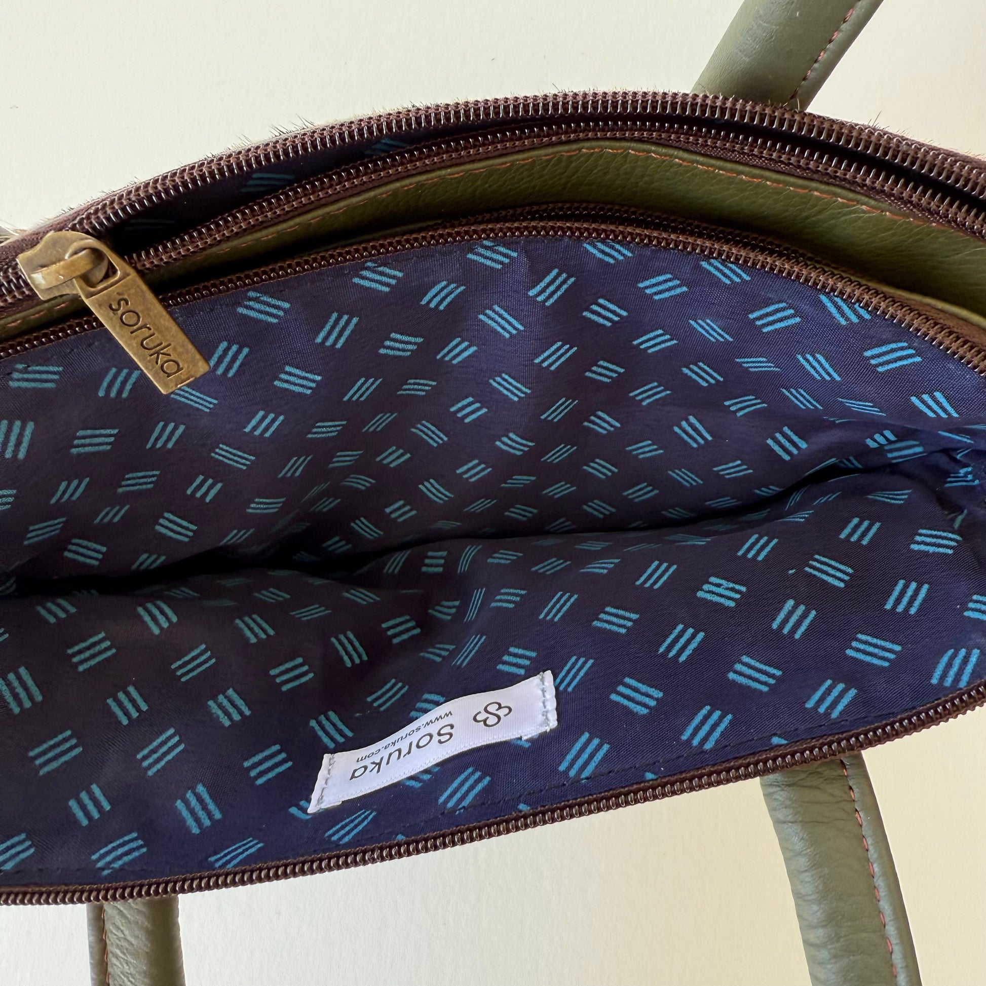top view of green leather handbag showing blue patterned interior lining