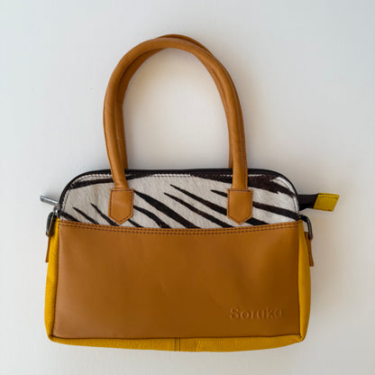 wheat brown colored leather handbag with black and white patterned accent