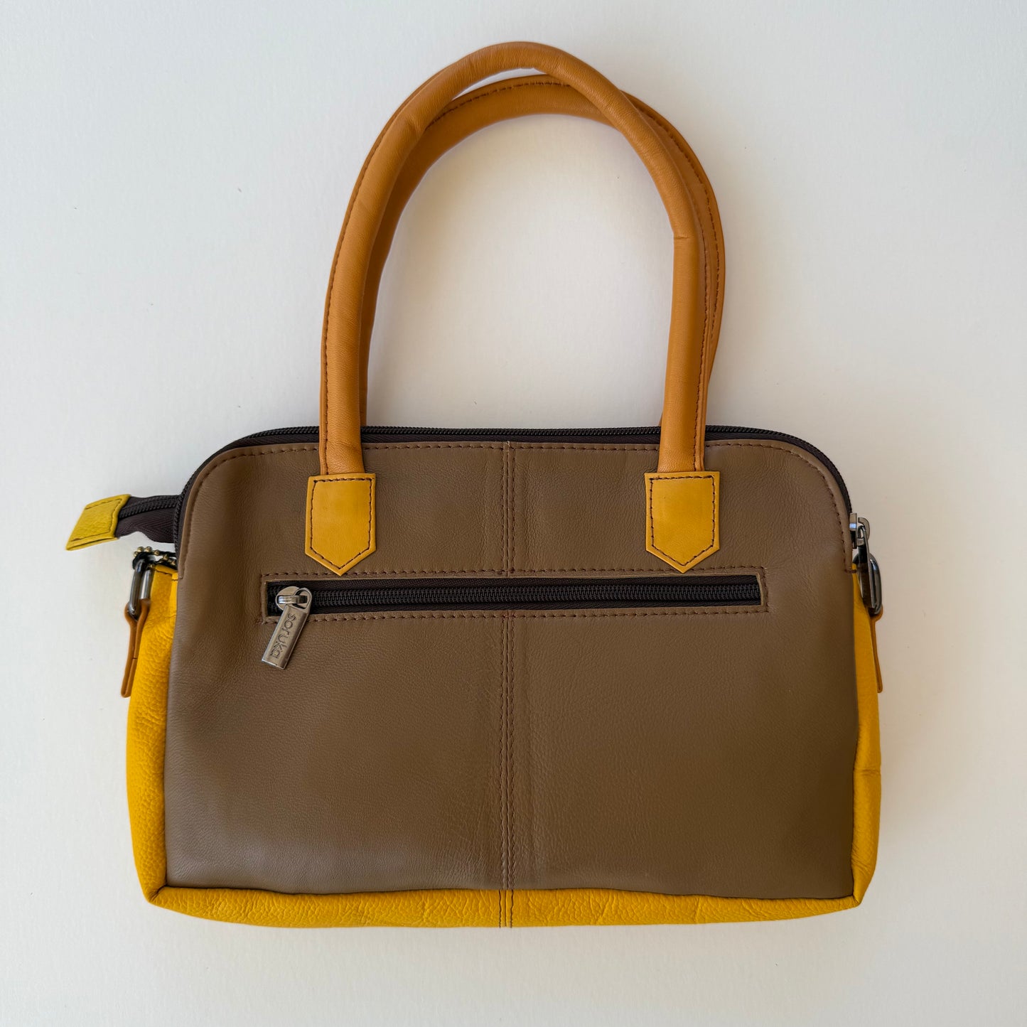 back view of wheat colored leather handbag with zippered pocket