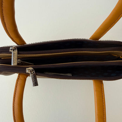 tope view of wheat colored leather handbag showing 3 zippered compartments