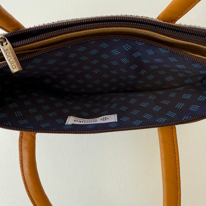 interior top view of wheat colored leather handbag showing blue patterned lining