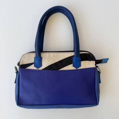 blue leather handbag with black and white accents