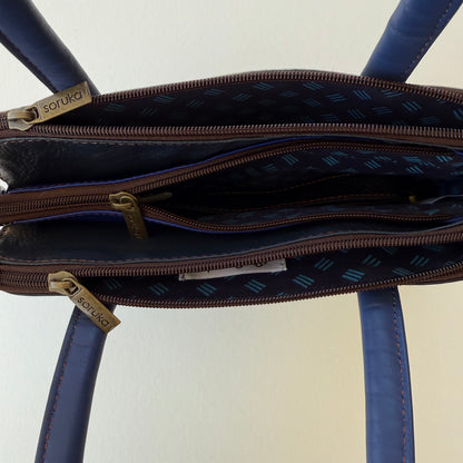 top view of blue leather handbag showing 3 zippered compartments