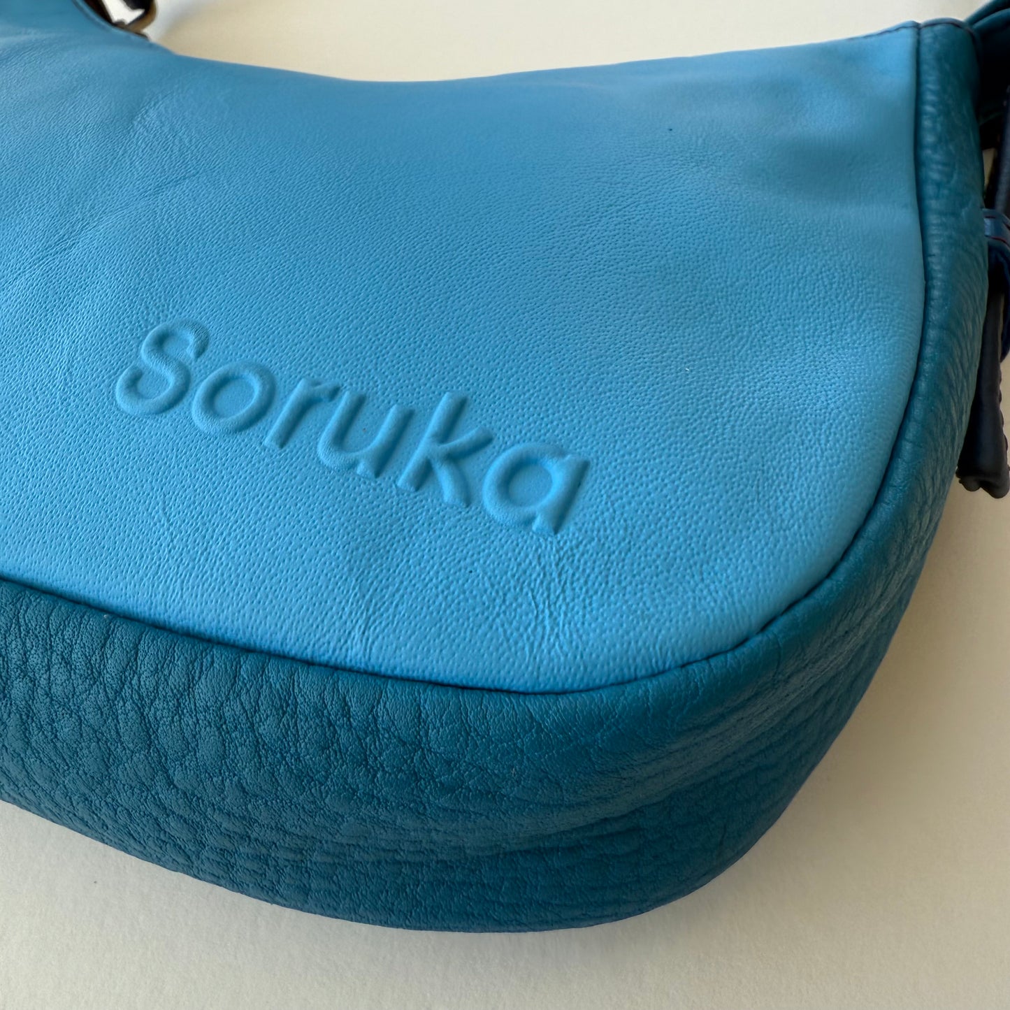 close-up of side view of blue leather handbag
