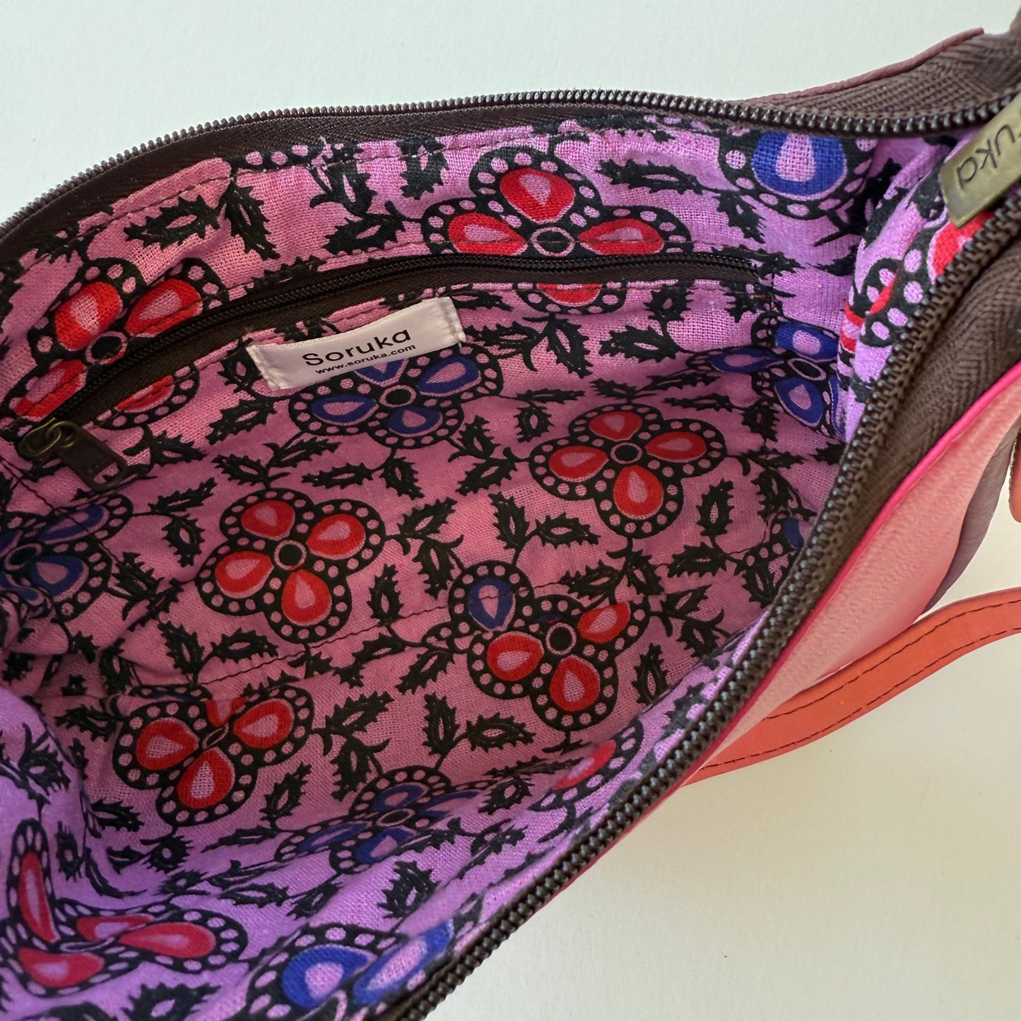 interior view of pink leather handbag with pink and blue floral lining