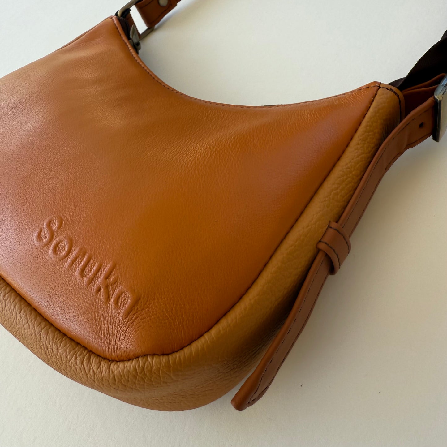 side view of light brown leather handbag on a white background