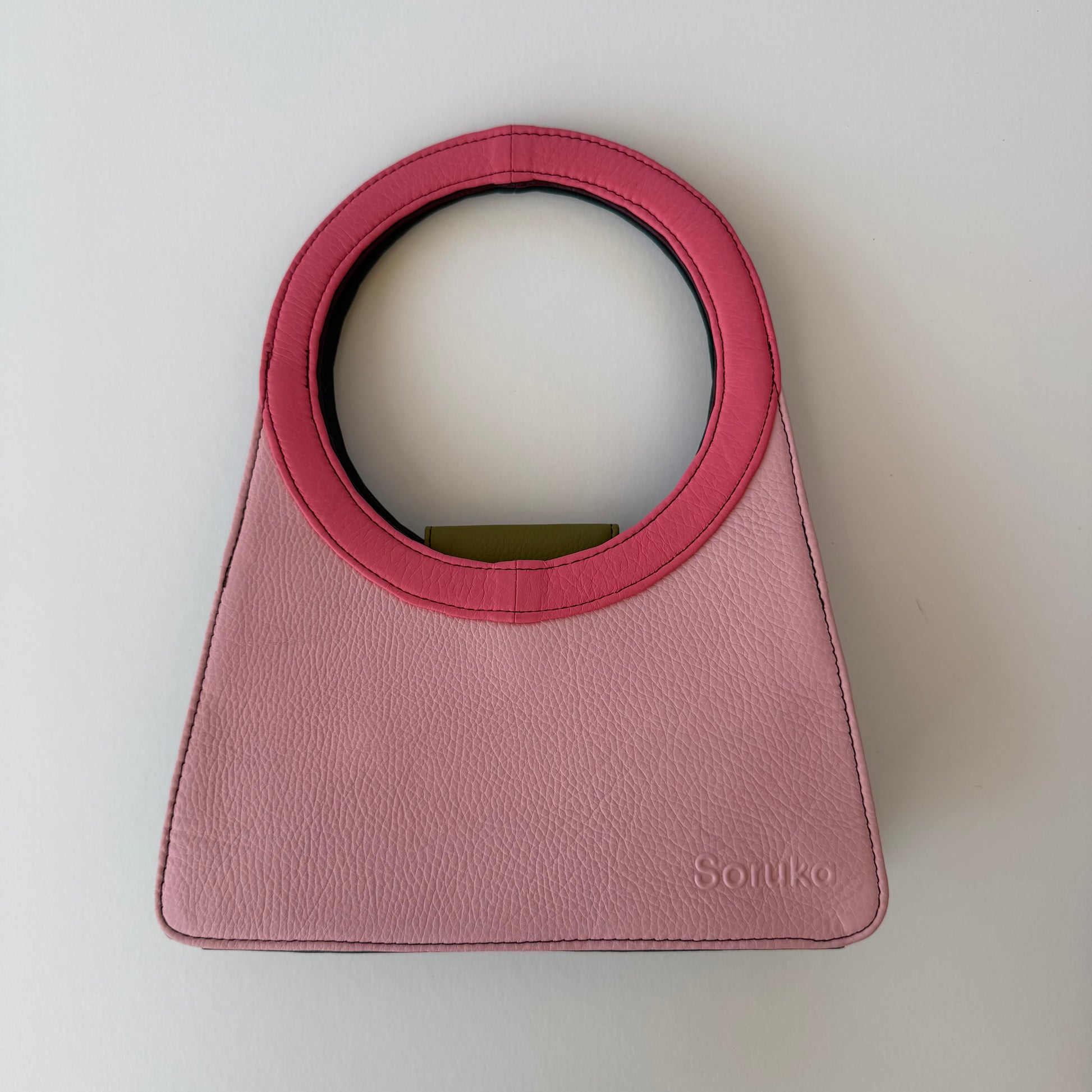 light Pink handbag with bright pink ring handle on a white background