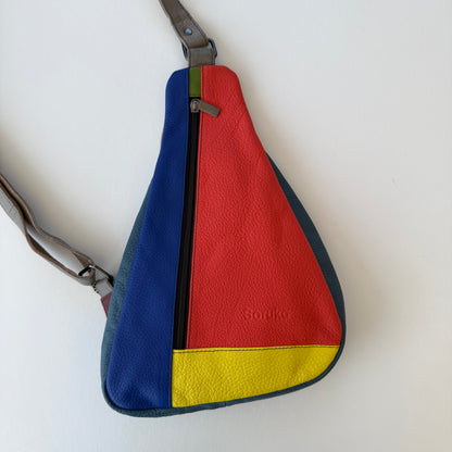 Colorful sling bag with blue, red, and yellow sections on a white background