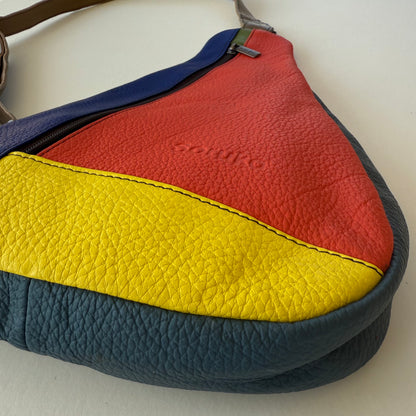 close-up of bottom corner of Colorful leather handbag with red, yellow, and blue sections on a white background