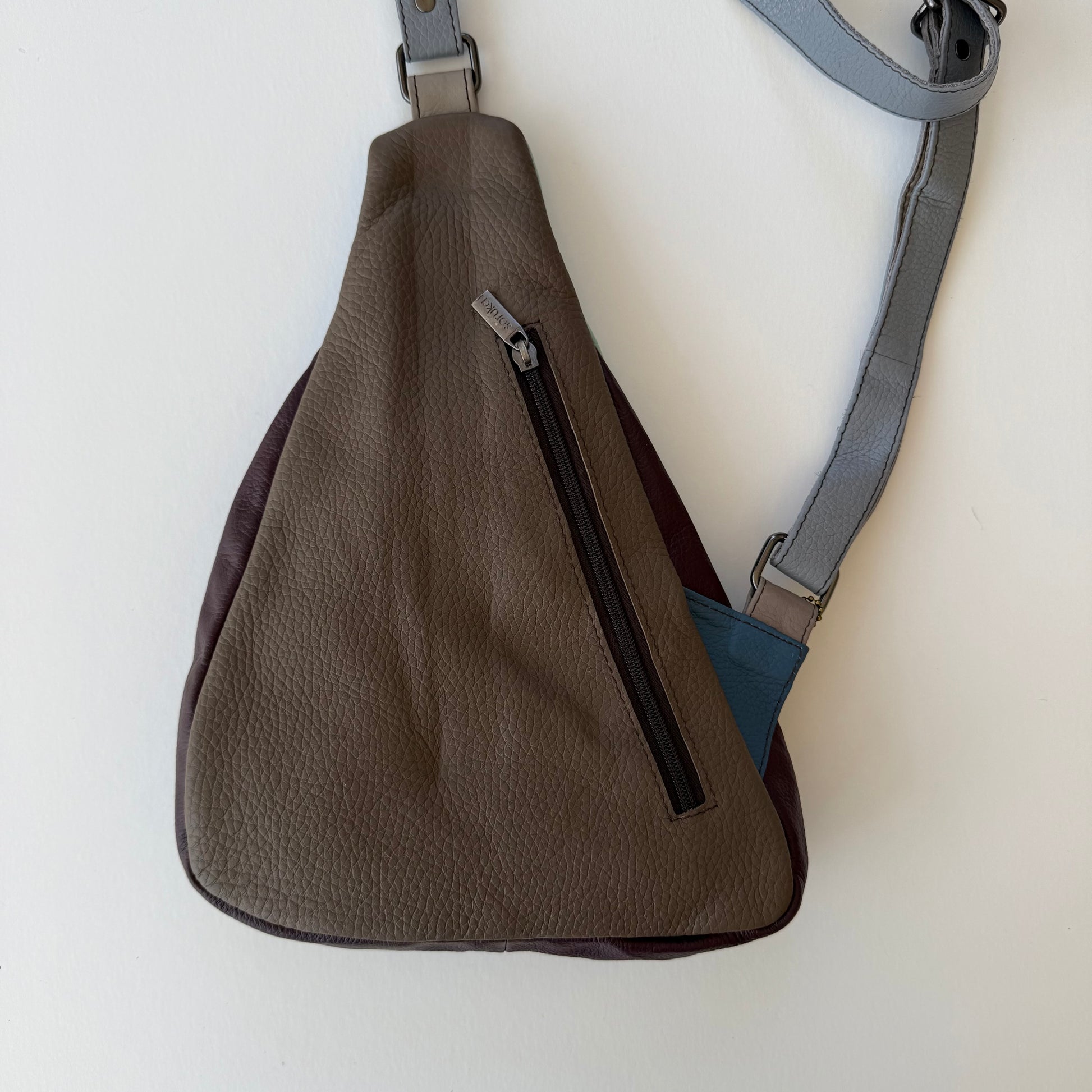 back view of Brown sling bag with a visible zipper on a white background