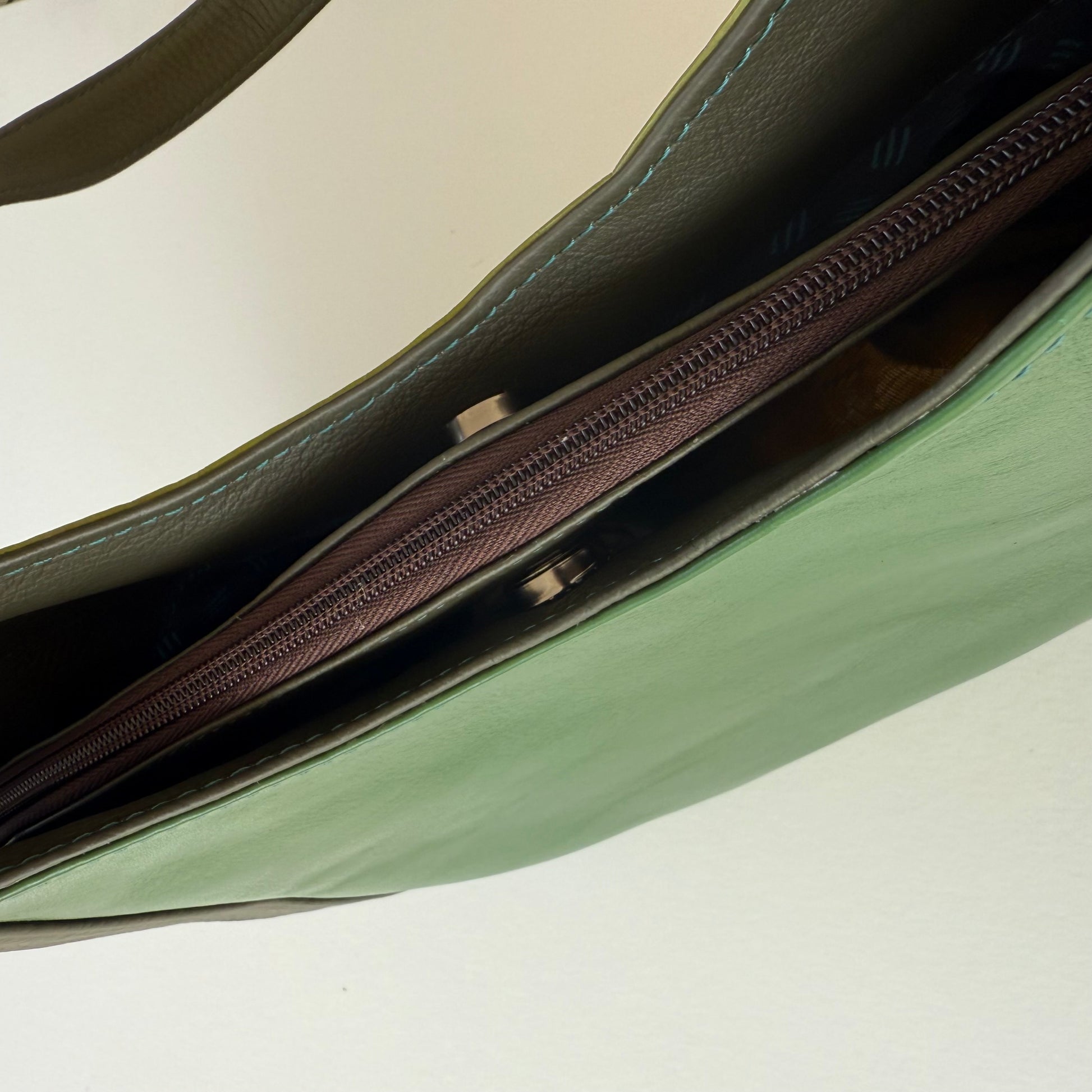 top view of green leather shoulder bag snapped closed