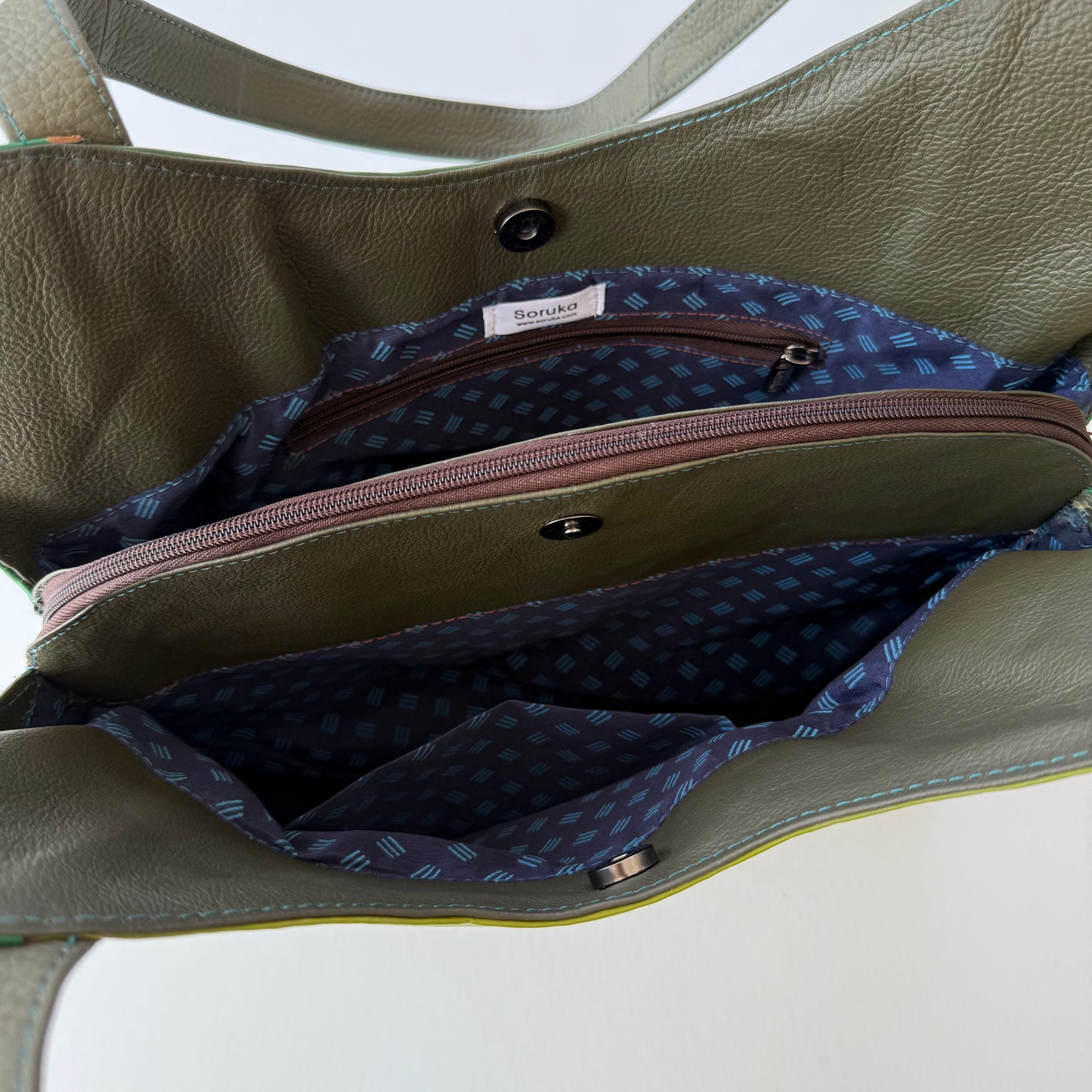 top view of green leather shoulder bag unsnapped