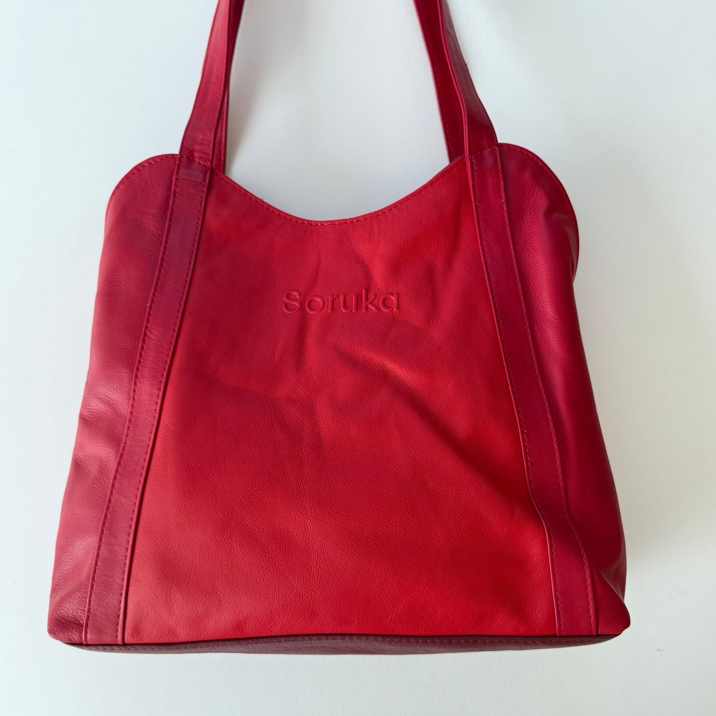Red handbag with 'Soruka' branding on a white background