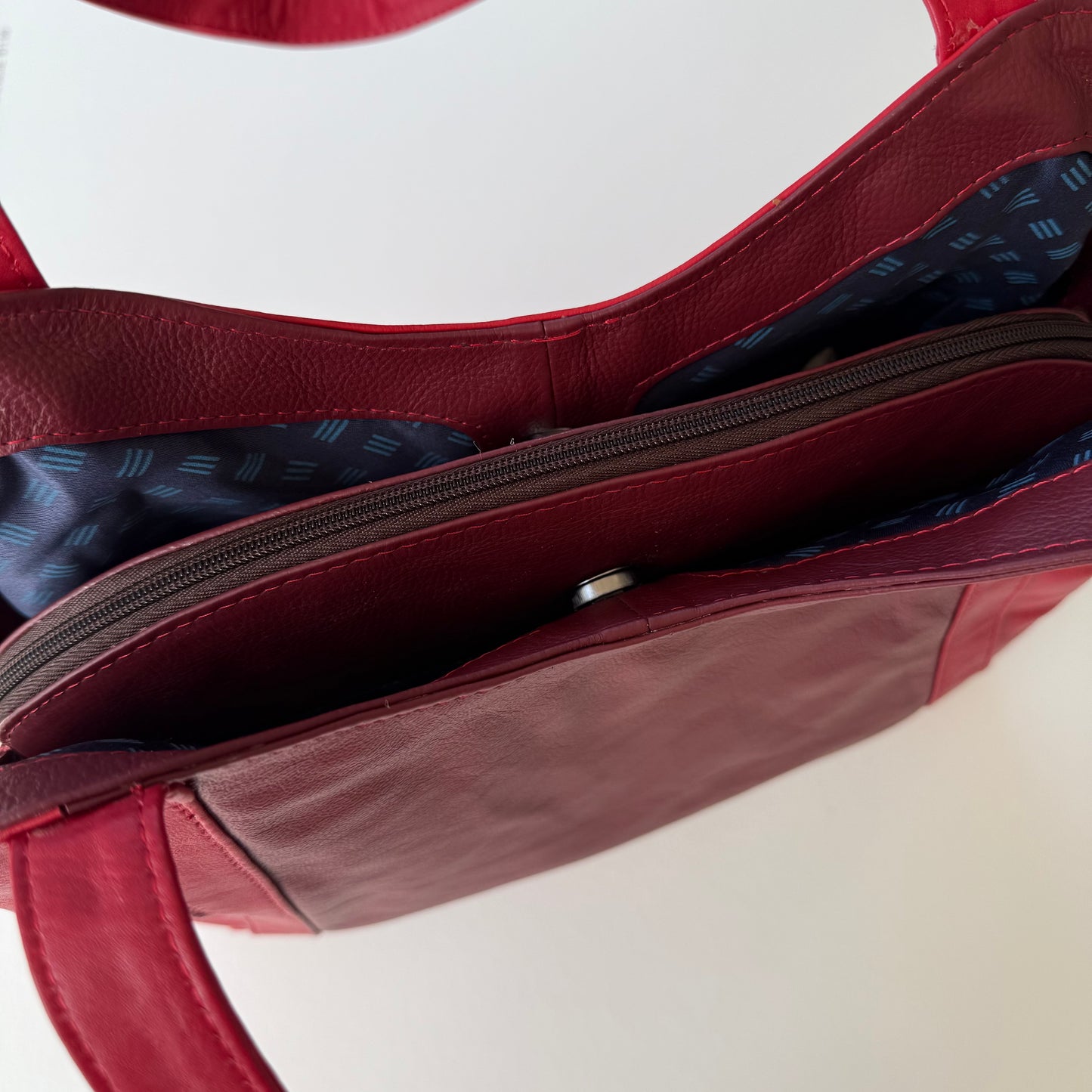 top view of a red leather bag with zipper closed 