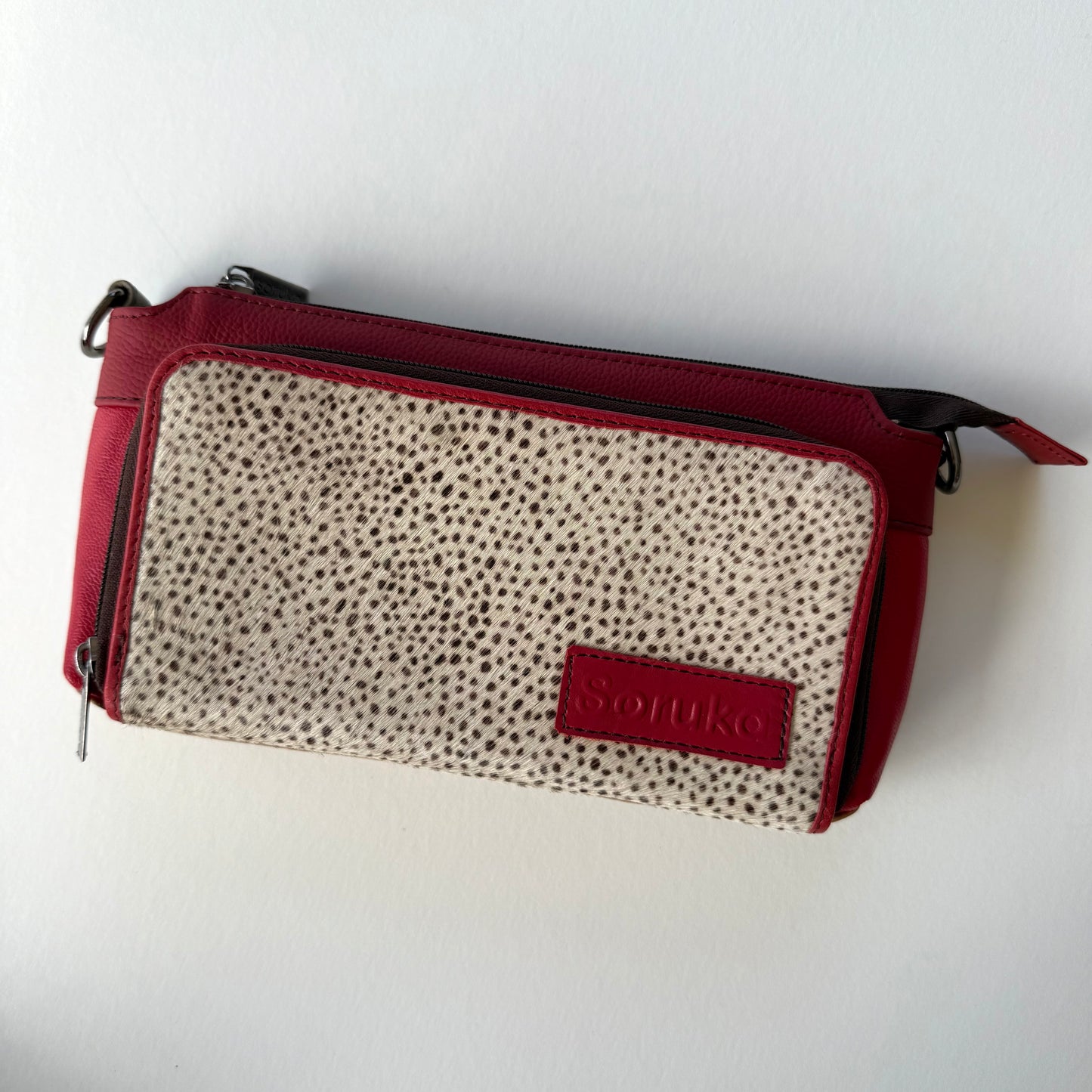cranberry madison crossbody with red body and black and white animal print front pocket